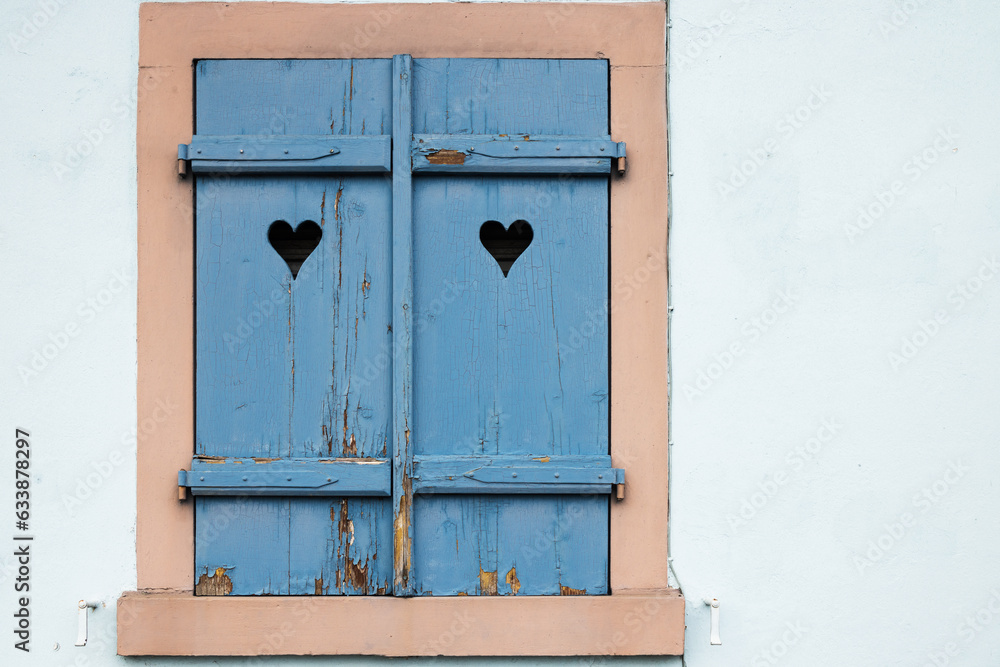 Old blue window with close shutters, hearts on shutters, blue background