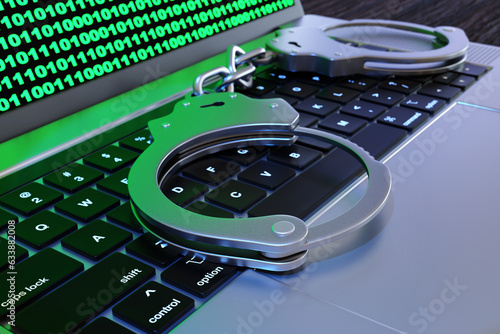 Fotografi Handcuffs on the keypad of laptop showing binary code on screen