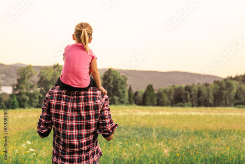 Fototapeta Naklejka Na Ścianę i Meble -  Young father and child walking in a meadow enjoying time bonding in nature together 
