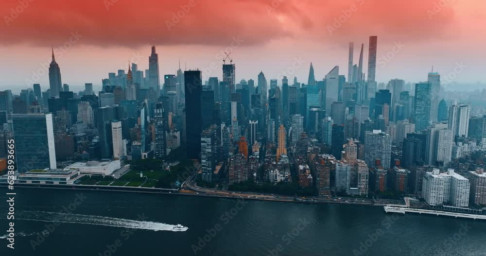 Pink sky and heavy cloudscape above the Midtown of New York. Drone footage above the river with yacht floating on. Pink sky and heavy cloudscape above the Midtown of New York. Drone footage above the river with yacht floating on.