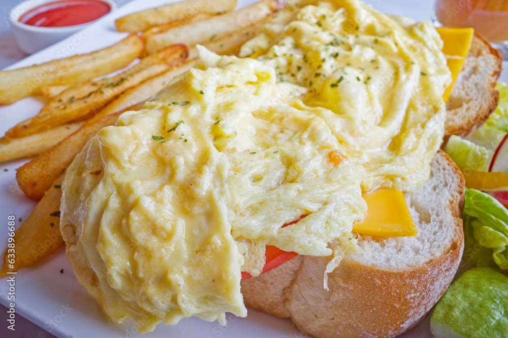 Cheese scram bled egg, white bread loaf, mixed greens and french fries on the plate Cheese scram bled egg, white bread loaf, mixed greens and french fries on the plate