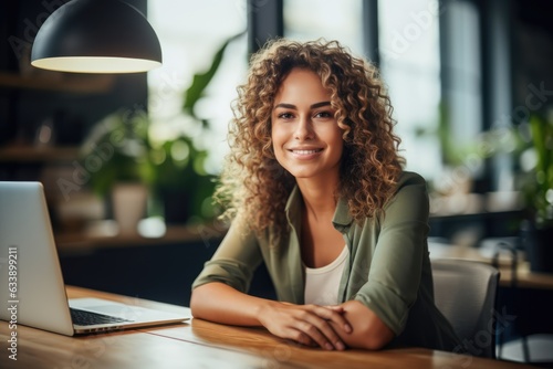 Young smiling businesswoman sitting at her desk in a light-filled modern office