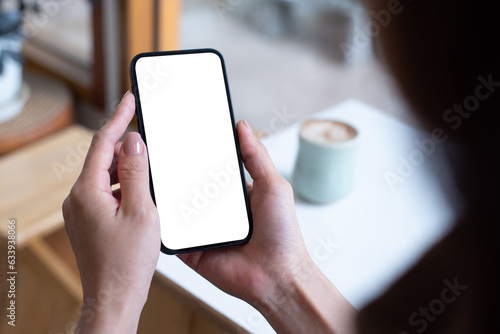 Mockup, woman\'s hand holding using mobile phone at coffee shop with copy space, white blank screen for text, mobile app design and advertising, online marketing