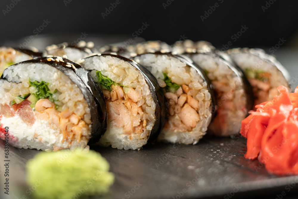 sushi roll futomaki with cucumber and fried salmon on a black stone plate. sushi roll futomaki with cucumber and fried salmon on a black stone plate.
