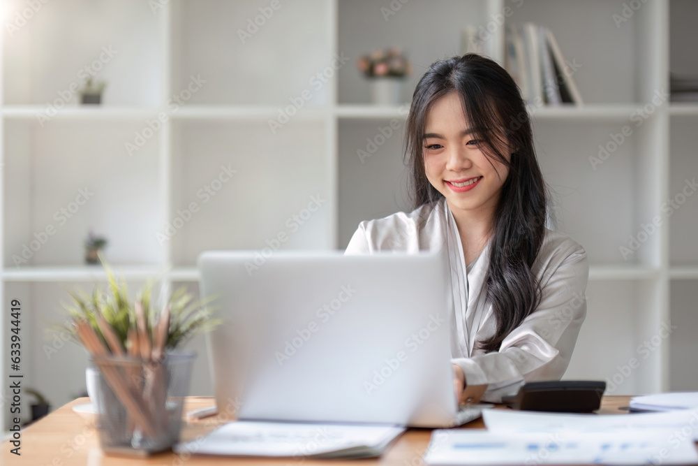 Asian Business woman using laptop for doing math finance on an office desk, tax, report, accounting, statistics, and analytical research concept Asian Business woman using laptop for doing math finance on an office desk, tax, report, accounting, statistics, and analytical research concept