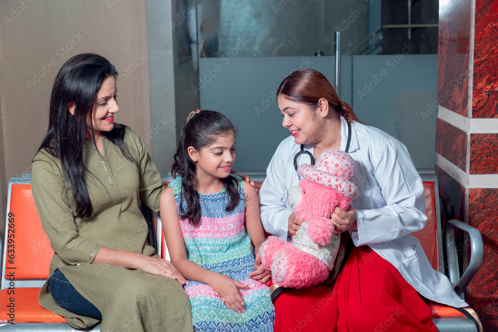Indian female doctors caring and smiling with little girl at hospital