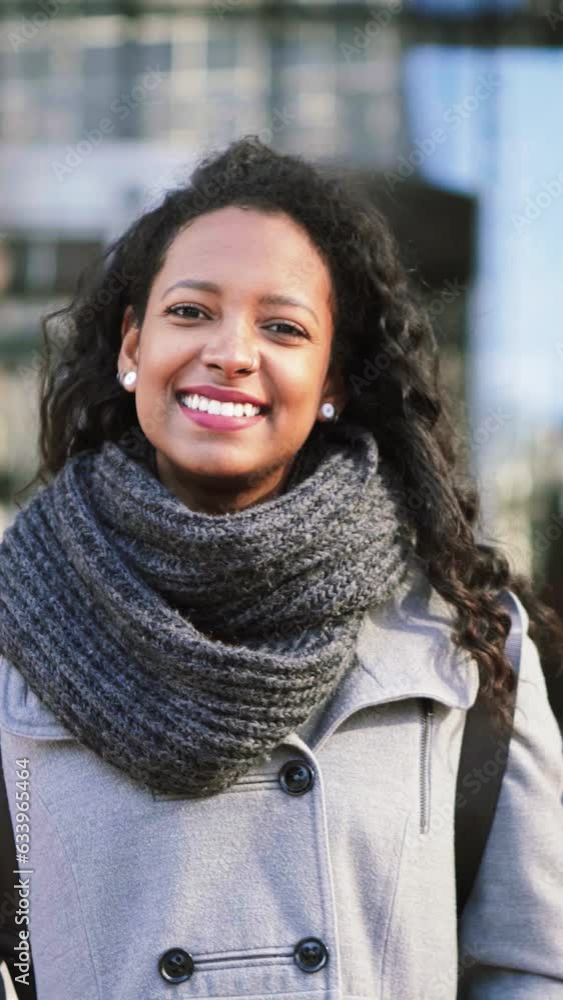 Vertical individual close up portrait of a young hispanic employee woman smiling and looking at camera, at the background an modern office city building. Business Concept. High quality footage Vertical individual close up portrait of a young hispanic employee woman smiling and looking at camera, at the background an modern office city building. Business Concept. High quality footage