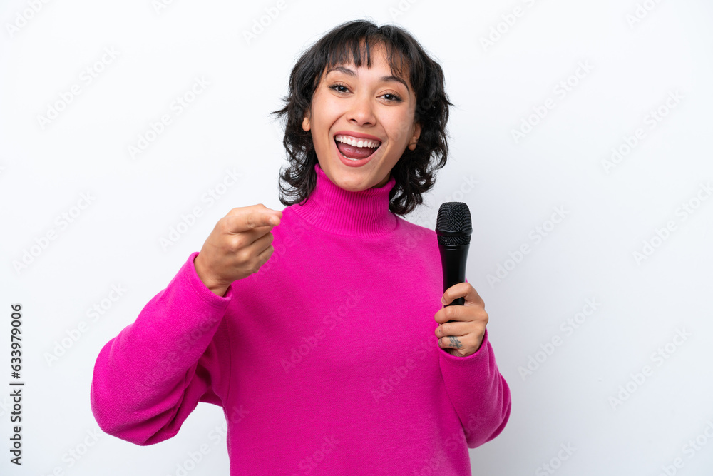 Young Argentinian singer woman isolated on white background surprised and pointing front Young Argentinian singer woman isolated on white background surprised and pointing front