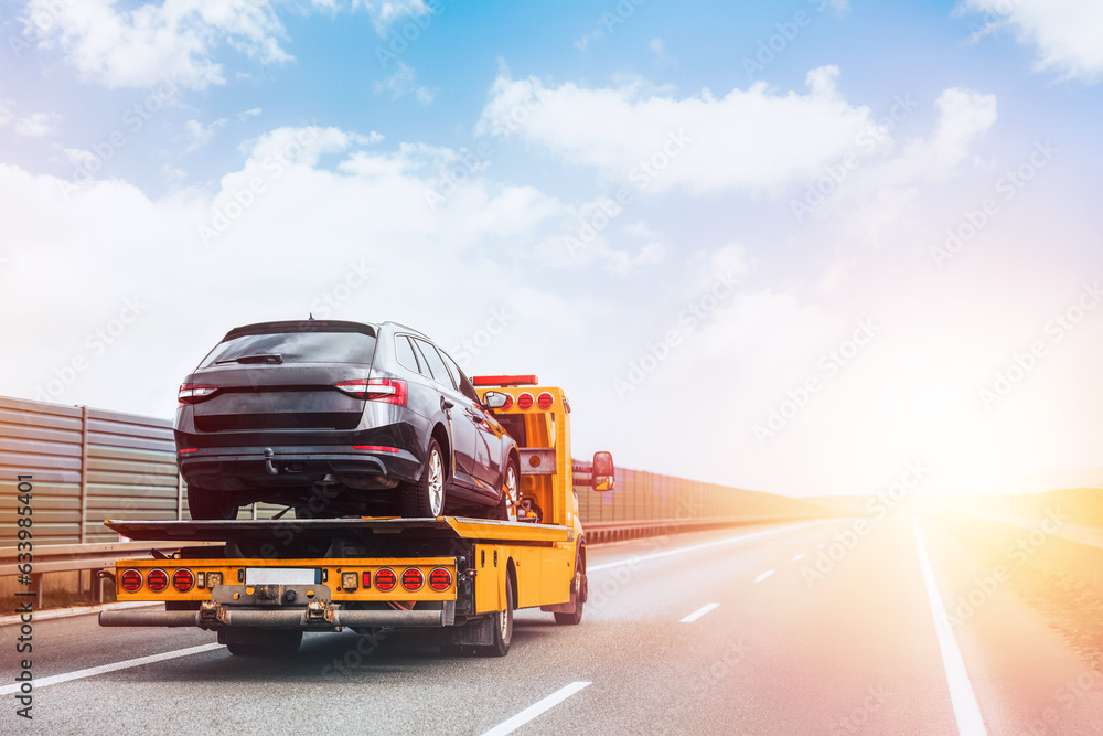 A tow truck on the public road. Tow truck with broken car on country road. Tow truck transporting car on the highway. Car service transportation concept. A tow truck on the public road. Tow truck with broken car on country road. Tow truck transporting car on the highway. Car service transportation concept.