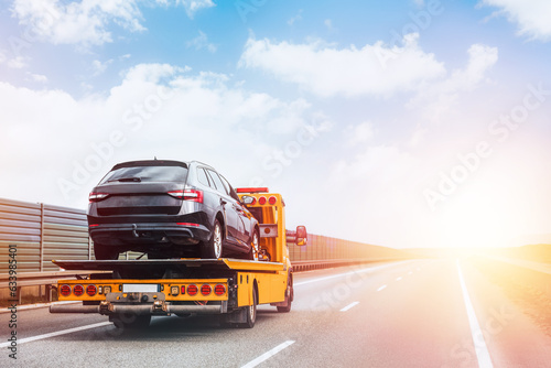 A tow truck on the public road. Tow truck with broken car on country road. Tow truck transporting car on the highway. Car service transportation concept. photo