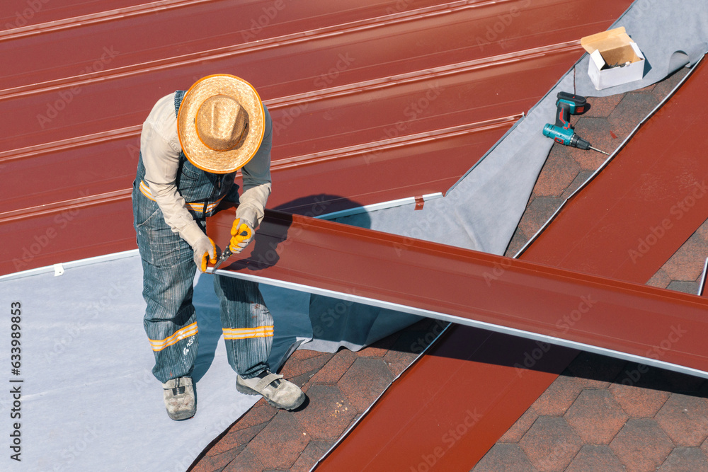 Professional construction worker changing the roof membrane of a building with metal roof sheet. Worker making maintenance on roof. Building renovation. Aluminum or steel roofing, Professional construction worker changing the roof membrane of a building with metal roof sheet. Worker making maintenance on roof. Building renovation. Aluminum or steel roofing,