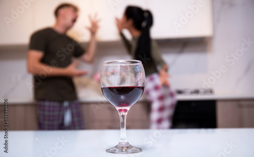 Romantic couple flirting with each other with wine on valentine’s night date at home in the kitchen.