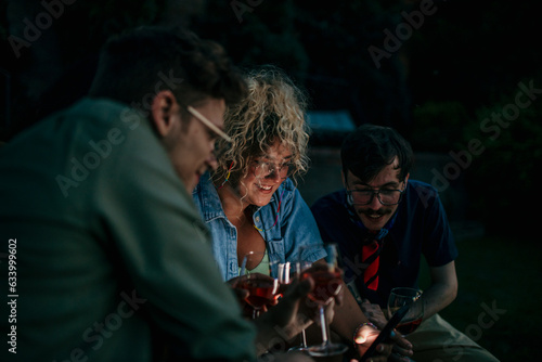 Friends looking together on the phone during a dinner party.