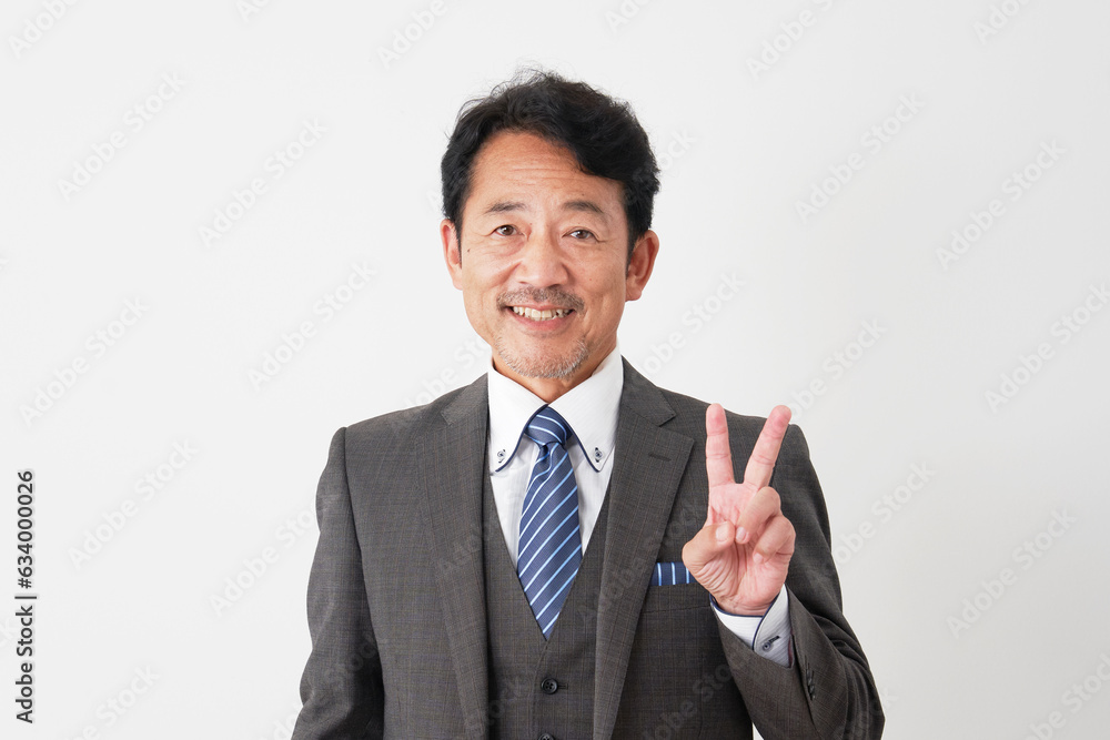ピースサインをするミドルエイジのビジネスマン　白背景