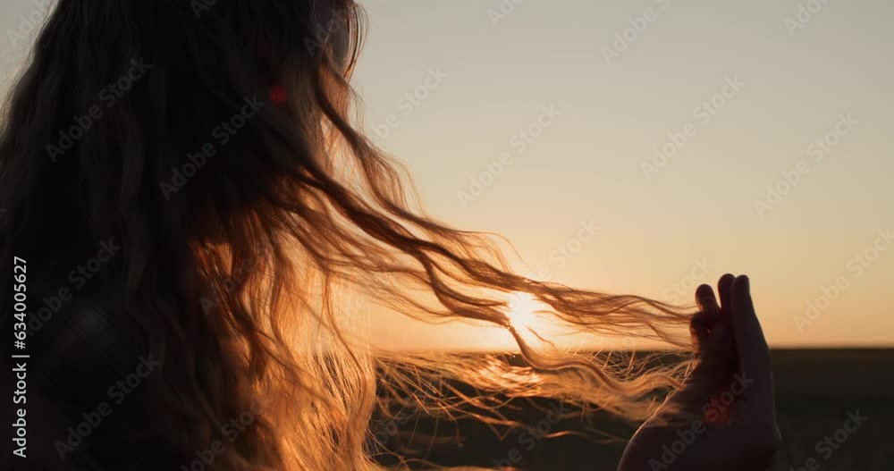 Teen looks at her hair in the sun, holds a lock of hair in her hand Teen looks at her hair in the sun, holds a lock of hair in her hand