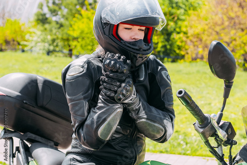 A girl in a motorcycle protective helmet puts on gloves © ir1ska