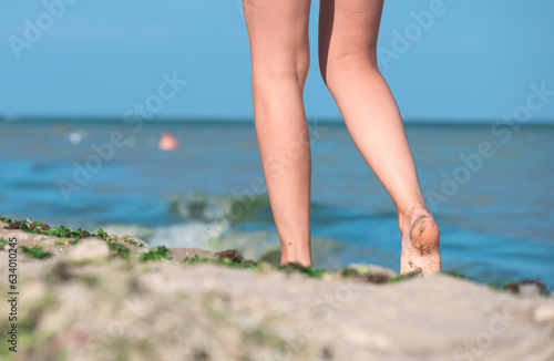 Woman's feet on the beach sand. The woman was walking on the beach, at the edge of the sea