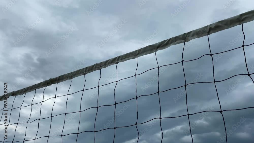 Volleyball net on the background of a cloudy sky. White net, play volleyball. Sports in bad weather, beach games. A thunderstorm is approaching, cancellation of the match Volleyball net on the background of a cloudy sky. White net, play volleyball. Sports in bad weather, beach games. A thunderstorm is approaching, cancellation of the match