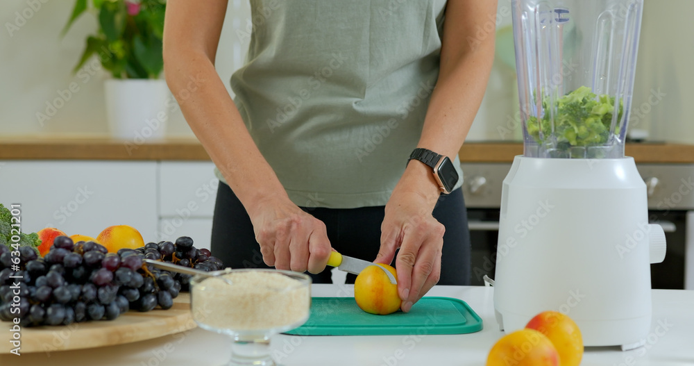 Young woman makes a smoothie with broccoli and peaches in a blender