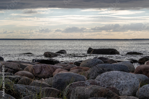 Sunset view from parispea beach in Lahemaa national park, Estonia. Image shows sunset with partial clouds and a calm sea washing over the rocky beach. August 2023 © J.Woolley