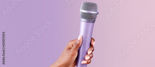 A lilac background with a woman s hand holding a microphone photo