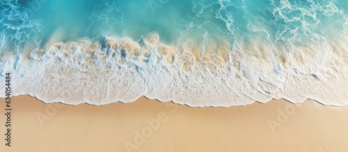 Aerial view of a beach with clear blue water and sunlight representing summer vacation and natural beauty
