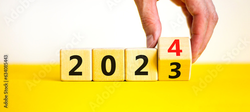 2024 happy new year symbol. Wooden cubes with number 2023 and 2024. Beautiful yellow table white background, copy space. Businessman hand. Business and 2024 happy new year concept.