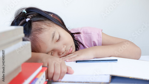 Portrait Of Cute Little Asian Female Child Sleeping At Desk Tired After Doing School Homework, Exhausted Girl Using Of Books As Pillow, Napping At Table At Home, Closeup Shot, Free Space.
