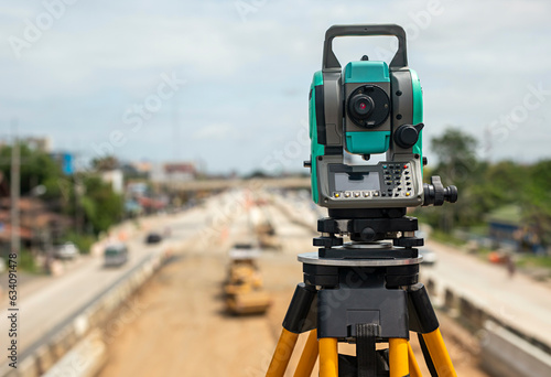 Close-up of surveyors equipment (theodolite) on the construction site of the road with construction machinery background. © Pituk