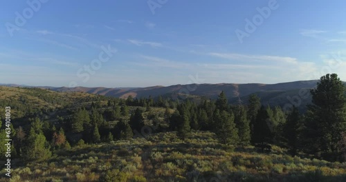 Eastern Oregon moving drone aerial of forests and canyon with high clouds and long shadows