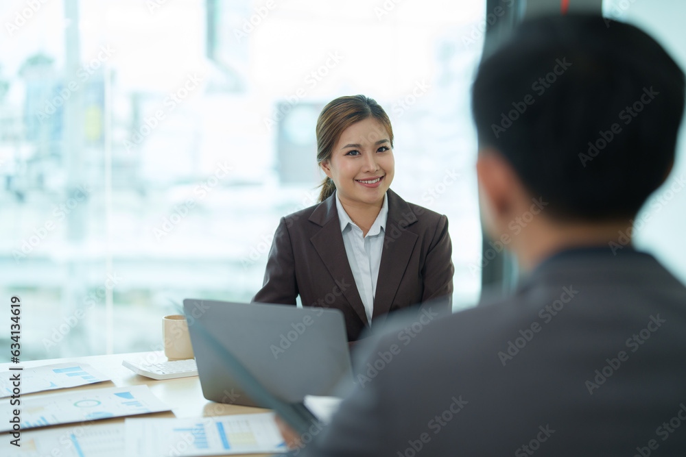Group of diverse businesspeople using a laptop while working together in a modern workspace. Group of diverse businesspeople using a laptop while working together in a modern workspace.
