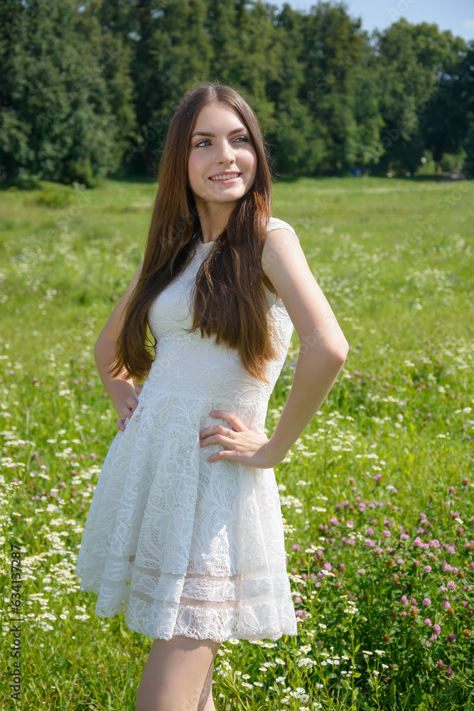 Beautiful young smiling woman in a flowery meadow in a white dress Beautiful young smiling woman in a flowery meadow in a white dress