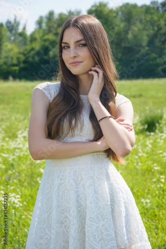 Beautiful girl in a flowery meadow in a white dress in summer