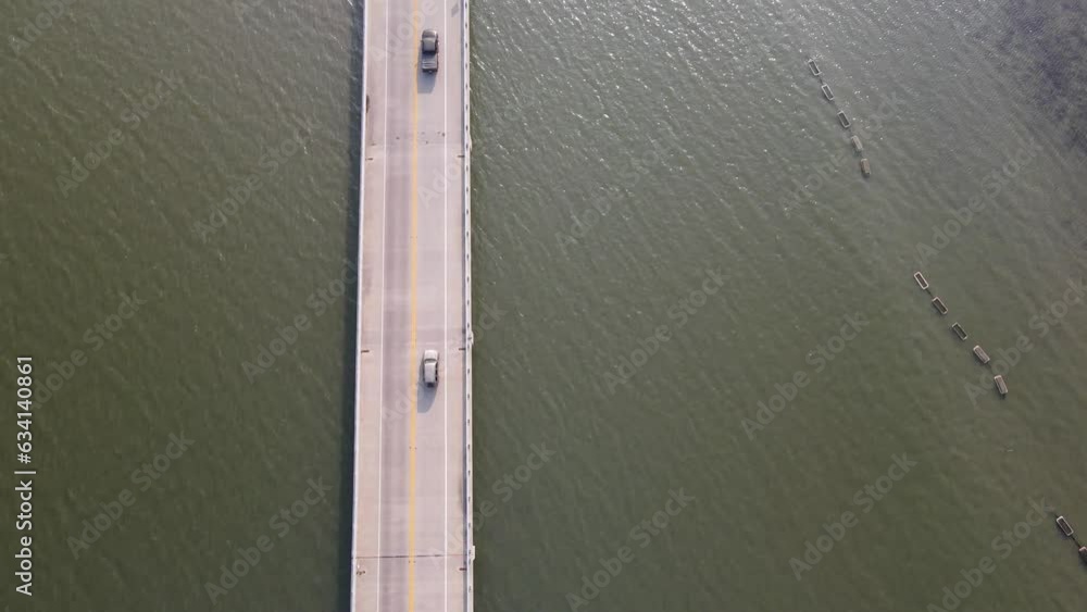 Top view of the bridge across the bay, the road vertically splits the image, cars cross the frame.
Top view of the bridge across the bay, the road vertically splits the image, cars cross the frame.