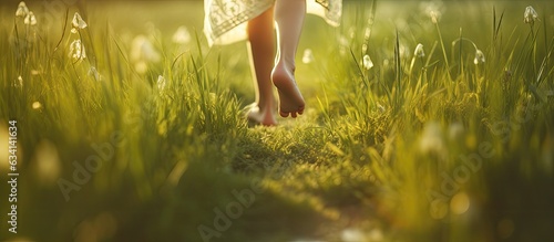 Happy child running barefoot outdoors on green grass at sunset representing the concept of a joyful childhood