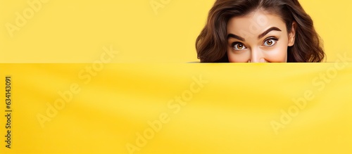 A joyous young woman glances out from behind a white banner against a yellow background with space for text © HN Works