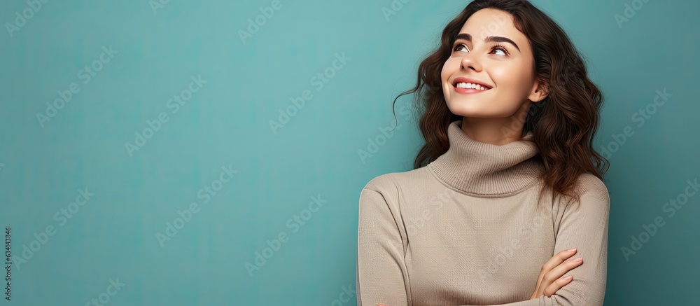 An attractive young woman full of joy confidence and optimism gazes upwards with her arms crossed An attractive young woman full of joy confidence and optimism gazes upwards with her arms crossed