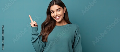 A young European woman in her 20s looking amused and excited points downwards and admires the camera while describing a captivating product and recomme