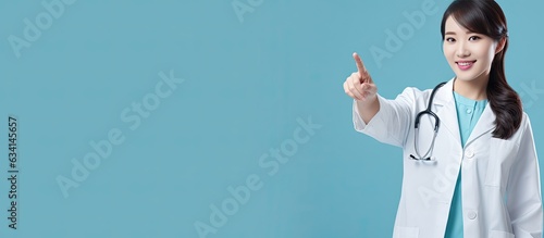 Blue background Asian doctor pointing studio shot
