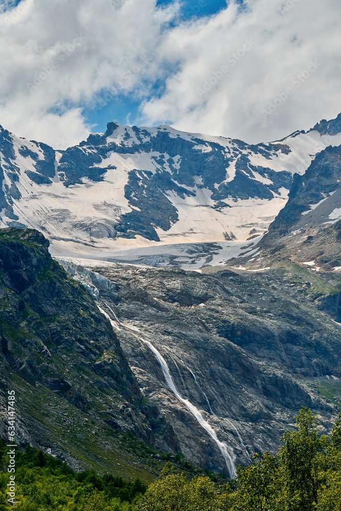 view of the glacier with a waterfall and a blooming meadow
