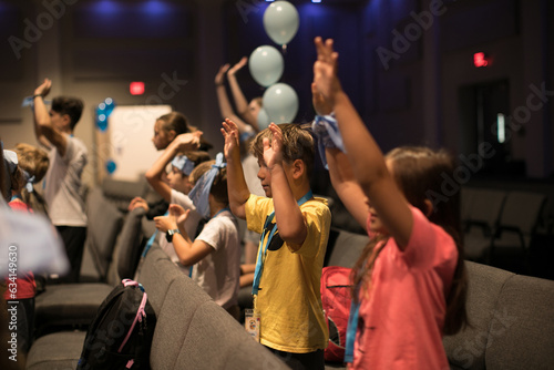 Group of little kids playing games, dancing in circle and having fun in camp