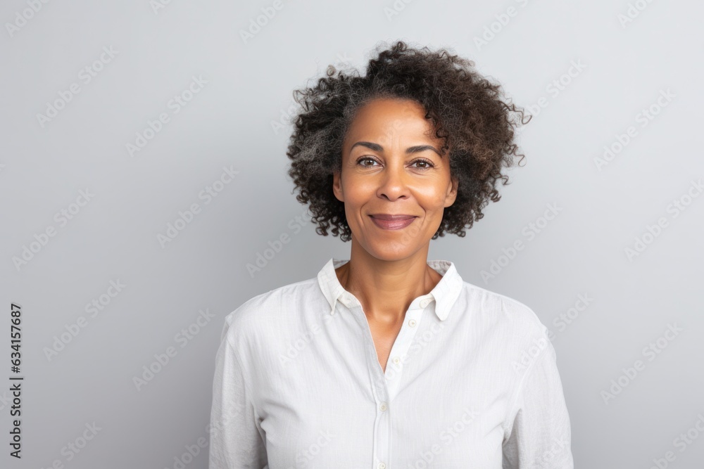 studio portrait of stylish middle age smiling 50 - 55 year old woman posing on grey background