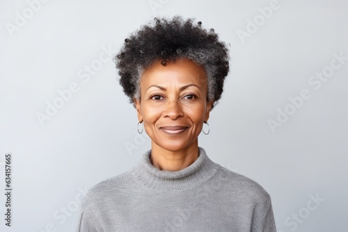 studio portrait of stylish middle age smiling 50 - 55 year old woman posing on grey background