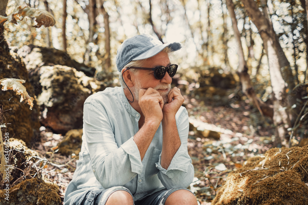 Portrait of pensive senior bearded man in black sunglasses sitting in park looking away Portrait of pensive senior bearded man in black sunglasses sitting in park looking away