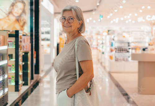 Obraz na plátně Smiling senior woman in shopping mall looking back at camera enjoying shopping activity