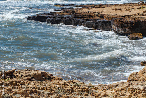 Flat stone rocks seashore, waves on the water