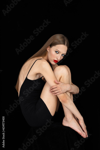 Portrait of beautiful young woman with a red lipstick on black background in studio