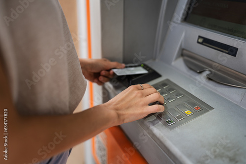 hands of woman using credit card and withdrawing cash at the ATM