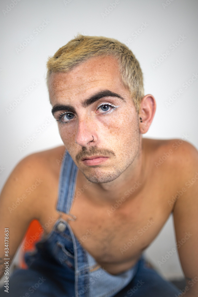 Thoughtful shirtless man sitting on chair near white wall in daylight Thoughtful shirtless man sitting on chair near white wall in daylight
