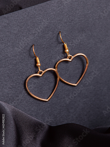 Earrings in the form of hearts. Costume jewelry for girls. Earrings on black background. Vertical